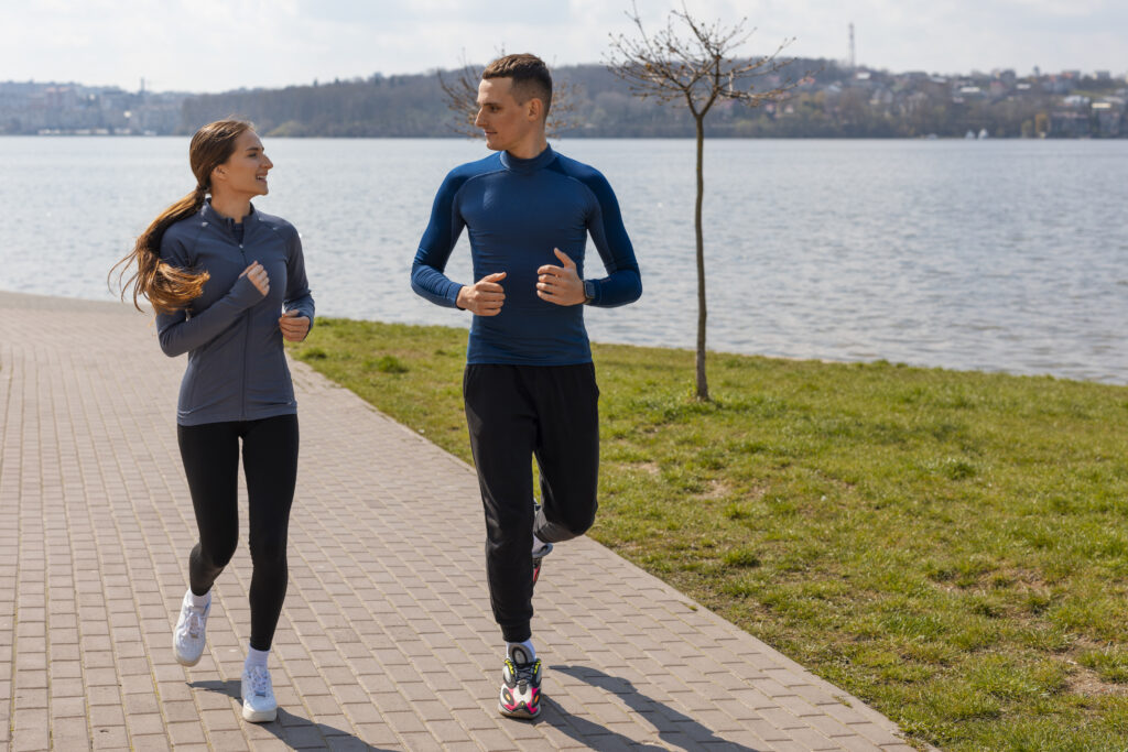 a man and woman running on a path near water